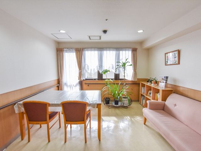 居心地の良い居室の風景 共有スペース  広々とした居室はゆったりとした時間が流れる心地よい空間です。自然光が入り、植物も配置されており、穏やかな日々を送ることができそうです。