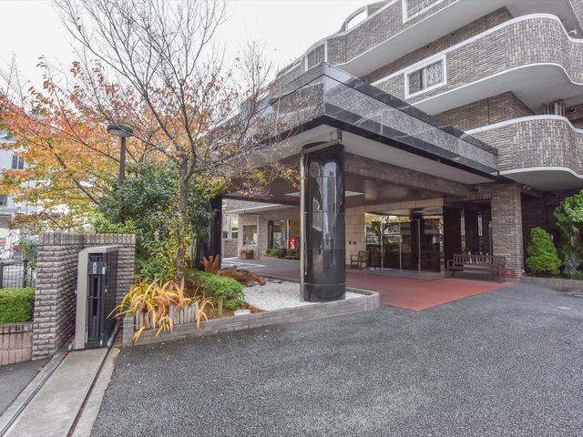 エントランスと緑の植栽 外観 落ち着いた雰囲気のエントランスは清潔感があり、来訪者を優しく迎え入れます。木々に囲まれた環境で心地よい出迎えを実感できるでしょう。
