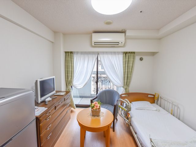 居心地の良い居室空間 居室 ベッドとテレビ、小さなテーブルが配された落ち着いた雰囲気の部屋です。個々のプライバシーが尊重された安らぎの空間となっております。