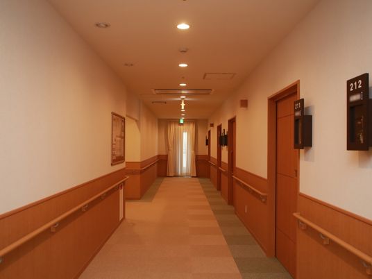 あたたかみのある色合いで統一された廊下。居室の入口には部屋番号が大きな文字で表示されていてわかりやすい。