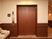 サムネイル 木目調のエレベーターの扉の前にソファが設置されている。エレベーターの扉、通路の腰壁、手すりが濃い茶色で、落ち着いた雰囲気の空間になっている。