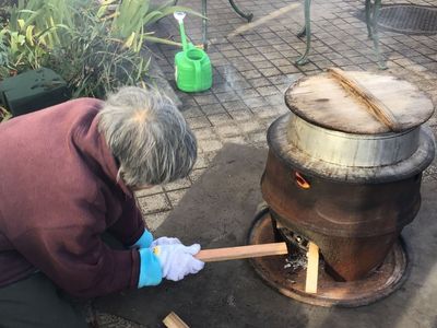 薪で火を扱う高齢者 中庭