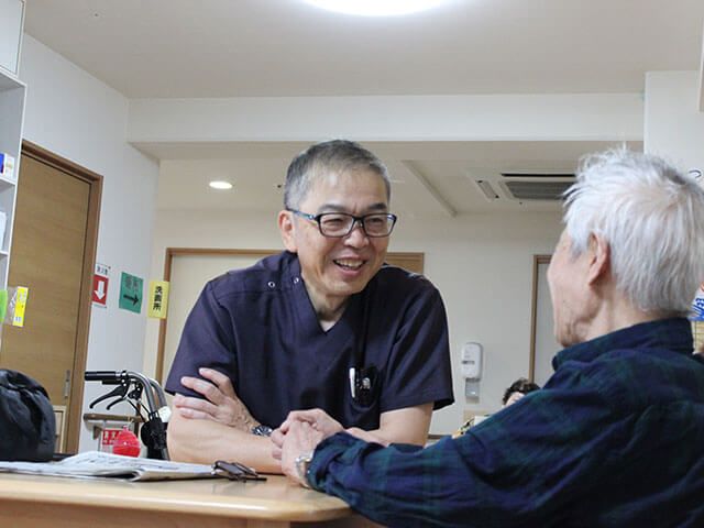 笑顔で会話するスタッフと利用者 スタッフイメージ 暖かい笑顔で会話を楽しむスタッフと利用者の様子です。安心感を感じるコミュニケーションが行われています。
