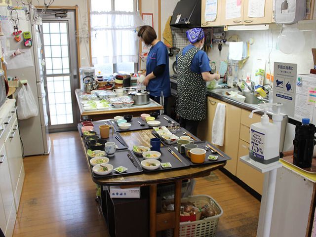 明るい食事準備の風景 キッチン 明るく清潔感のあるキッチンで、料理の準備が行われています。丁寧に整えられた食卓が、温もりを感じさせます。