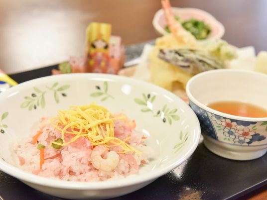 施設の写真 錦糸卵とエビの入ったちらし寿司や天ぷらなど、ひな祭りにちなんだ料理が黒いトレイに乗って提供されている。