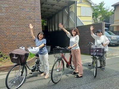 3人が自転車を停める外観