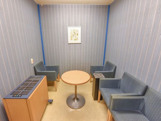 喫煙室の左端には、タバコ脱臭機が備え付けられている。円形テーブルや水玉模様のソファーチェア等が置いてある。