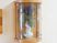 サムネイル 壁には木製と透明のカバーでできたディスプレイ用のケースが取り付けられている。中には白い花瓶に入ったお花が飾られている。