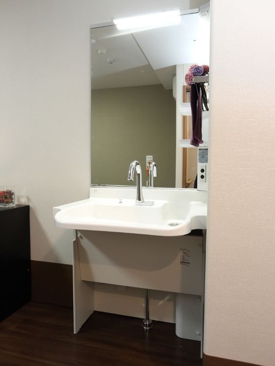 施設の写真 個室にある洗面台は流し台が広くつくられていて大きな鏡がついている。流し台は車いすの方も利用しやすい高さになっている。