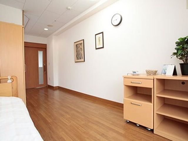 明るい居室の一角 居室 温もりを感じる木目調の床と、機能的な収納家具が配置されています。