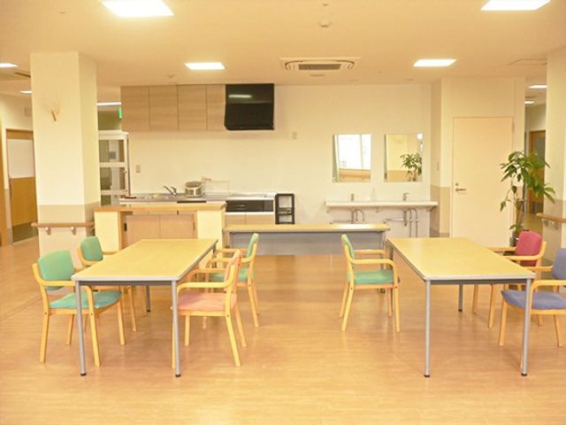 明るい食堂 食堂   広い食堂にテーブルと色違いの椅子が並び、ゆったり過ごせる雰囲気です。奥には配膳しやすいカウンターも見えます。