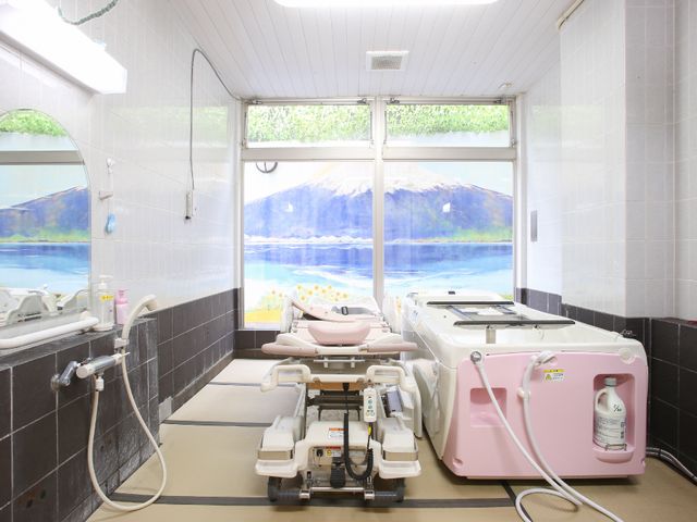 明るいリラックス浴室 介護用浴槽 清潔感のあふれる洗い場とバスタブが並ぶ浴室です。壁に描かれた海の絵がリラックスした気分を演出しています。
