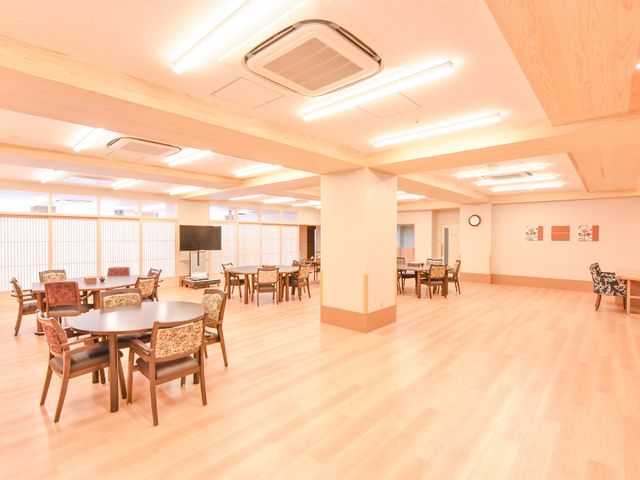 広々とした共有スペース 談話室 ゆったりとした多目的室では、日々の生活の中で様々なコミュニケーションを楽しむことができます。天井が高く、明るい照明の下でのびのびとお過ごしいただけます。