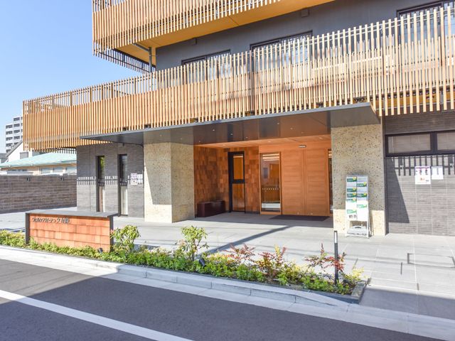 モダンな建物のエントランス 玄関 木目調と石を使ったエントランスは暖かみがあり、待合室の見える開放的な設計です。ここでの仕事が期待できそうですね。