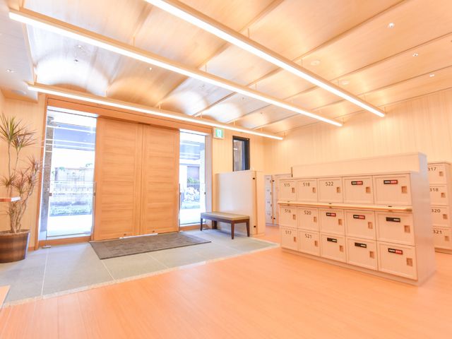 暖かみのあるエントランス風景 入口 木目調のエントランスは明るくて開放的です。荷物の受け渡しも便利な大きな郵便箱が並んでいます。