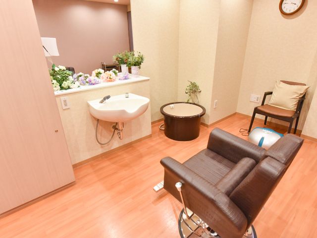 椅子と洗面台のある部屋 洗髪スペース ゆったりとした理美容室でのひとときを、ゆっくりとお過ごしいただけます。快適な環境で、ケアを重視した施設です。