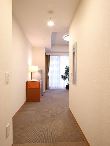 明るい廊下と居室の入口 居室 床と壁の色合いが温かみを感じさせ、リラックスできる場所です。居室への入口が清潔感のあふれる廊下から見えます。
