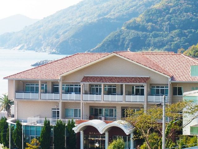海辺の施設外観 外観   赤い屋根と広い窓が印象的な建物です。海と山を望む落ち着いた環境で、働く場の雰囲気が伝わります。