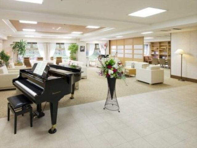 広々としたラウンジ風景 リビング 心地よい音楽が響くラウンジは、居心地の良い休息の場所です。ピアノの周りで、利用者の憩いのひと時を支えます。