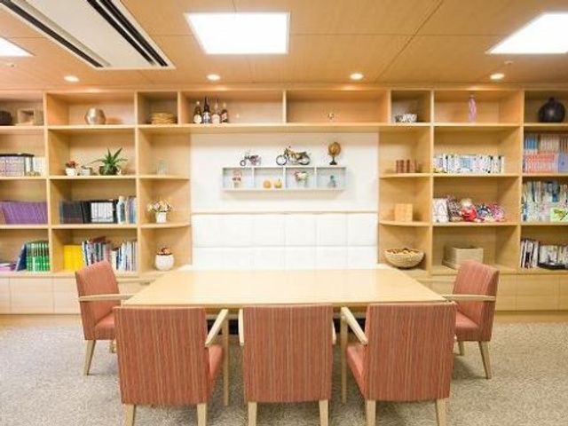快適な共有スペース コミュニケーションルーム ゆったりとした椅子が配置された温かみのあるラウンジです。壁には多彩な本や装飾品が並び、くつろぎの時間を過ごせる空間となっています。