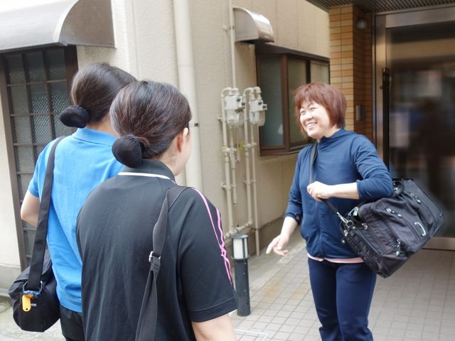 スタッフの外での様子 外観   建物の前でスタッフ同士が笑顔で会話しています。働く人の雰囲気が伝わり、職場の人間関係をイメージしやすい場面です。