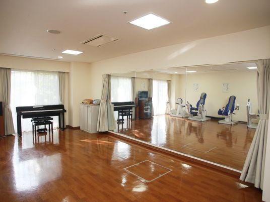艶のあるフローリングの広間。壁面一杯に鏡が張られており、ピアノや数種類のトレーニングマシンが置かれている。