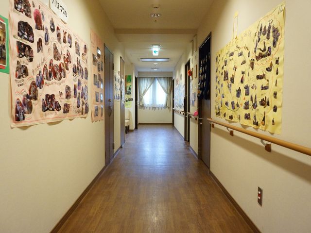 廊下に掲示物が飾られた空間 通路 壁には明るい色彩の掲示物があり、通りには手すりが設置されています。