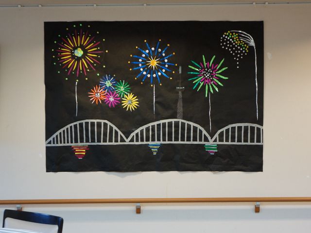 壁に飾られたカラフルな作品 手作り作品 カラフルな花火の絵が施された掲示物が、日々の暮らしに彩りを添えています。