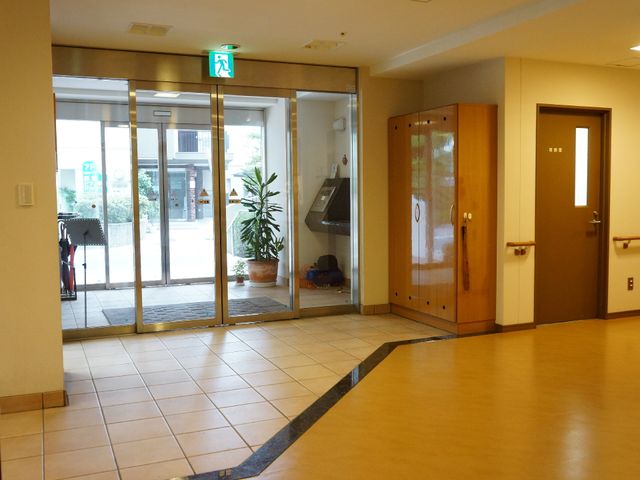 明るいエントランスの様子 エントランス 明るく開放的なエントランスは訪れる人を温かく迎え入れます。清潔感のある床と緑の植物が空間に彩りを加えています。