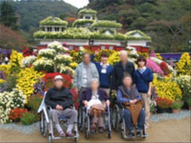 色とりどりの花と笑顔の方々 レクリエーション 充実した緑豊かな中庭で、訪れる方々が笑顔で憩っています。ゆったりと時間を過ごすことができる心地よい空間です。