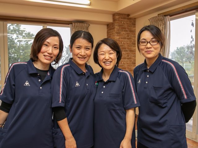 スタッフが笑顔で立つ様子 スタッフ 明るく笑顔で対応するスタッフの姿が心地よい環境を作り出しています。チームワークを感じながら働ける場所です。