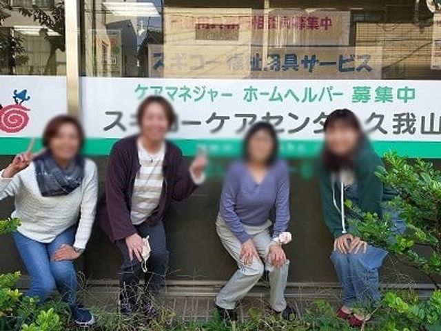 看板前に人が集う 看板 親しみやすい看板の前でスタッフが笑顔を見せる様子です。施設の雰囲気の良さが伝わります。