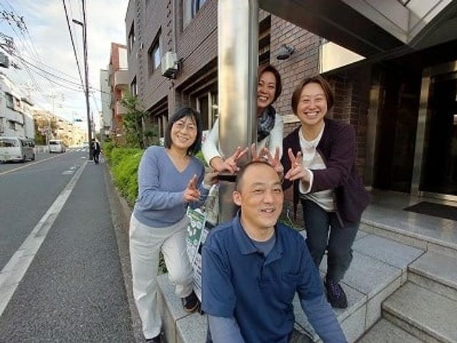 笑顔の人々が立つ入口前 エントランス   笑顔で撮影するスタッフたちが、施設のエントランスで歓迎しています。温かい雰囲気です。