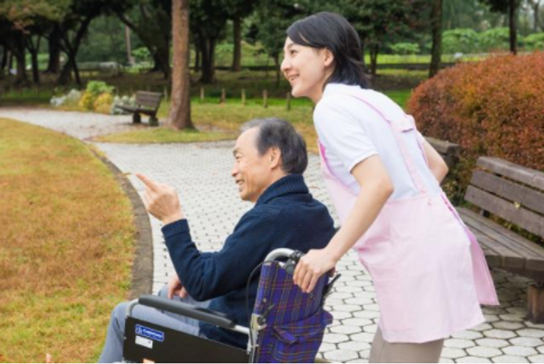 笑顔で車椅子を押す介護