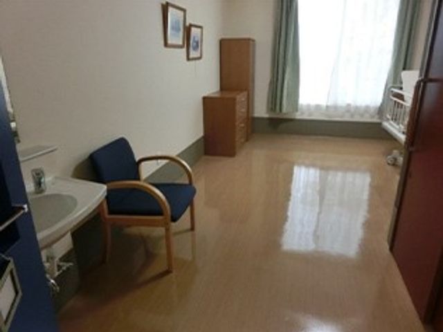 窓際の居室 居室   窓から自然光が入る、すっきりした居室です。椅子と収納家具があり、落ち着いて過ごしやすい印象です。