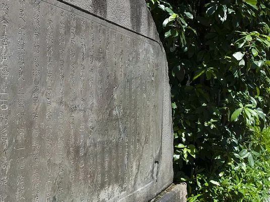 刻字のある石碑と緑の植え込み  