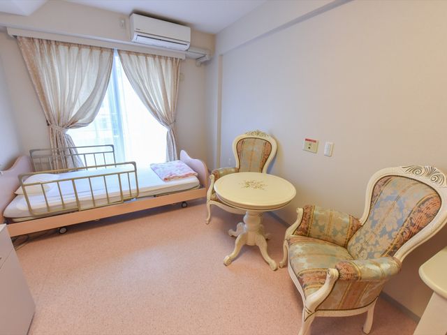ゆったりした居室のベッドと椅子 居室 ベッドとテーブルが備わった居室は、暖かい日差しを感じながらくつろげる空間です。心地良いチェアでゆっくりと過ごせます。