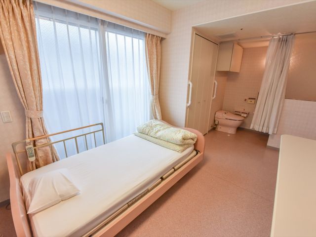 清潔感のある明るい居室 居室 ゆとりを感じさせる落ち着いた色合いの居室です。ベッドの横には広々としたスペースがあり、快適にお過ごしいただけます。