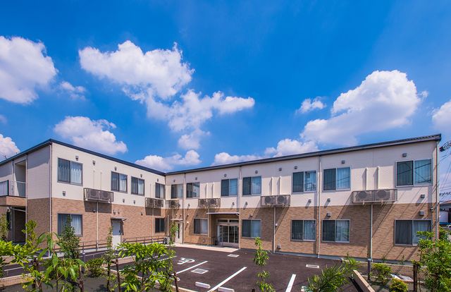 青空の建物外観 外観 青空の下、緑に囲まれた中庭を持つ明るい建物です。開放的な雰囲気が魅力的です。
