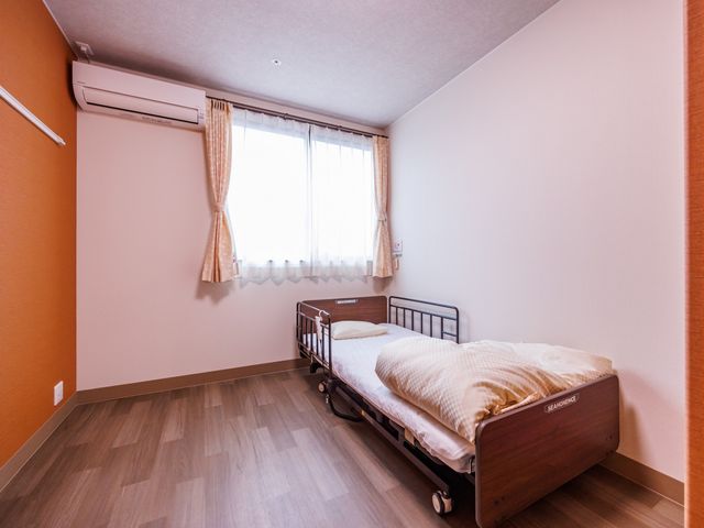 ベッドのある部屋 居室 広々とした居室で、心地よい自然光が差し込んでいます。快適な空間でくつろげます。