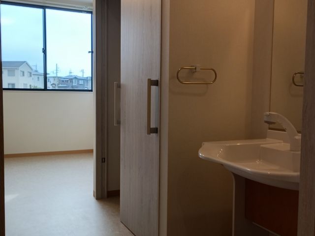 清潔感のある洗面台 居室 広々とした部屋には、使いやすい洗面台と大きな窓から自然光が差し込んでいます。