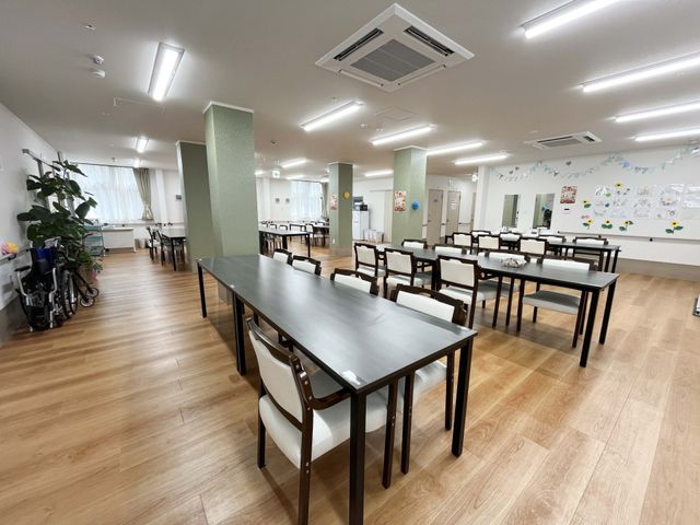 明るい食堂 食堂   広い食堂にテーブルがゆったり配置され、窓からの光で明るい雰囲気です。車椅子も通りやすそうで、働く場として動線が確認しやすいです。