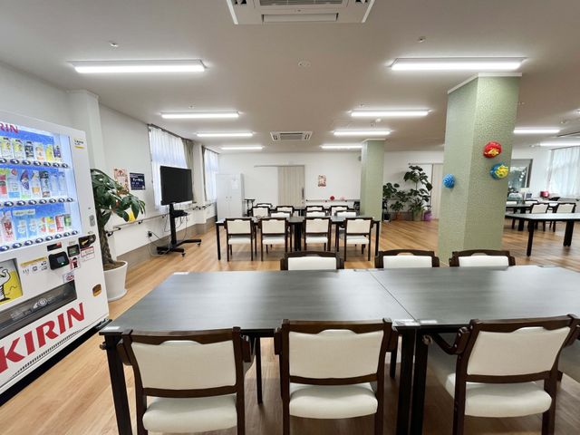 明るい食堂のテーブル席 食堂   広い食堂にテーブル席が整然と並び、テレビや自販機も見えます。ゆったり過ごしやすい雰囲気です。