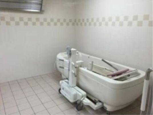 縦長の白い機械浴槽が置かれている。広めの浴室で、入浴介助をするスタッフが動きやすいように考えて作られている。