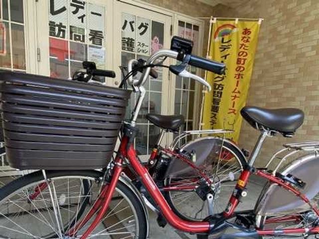 自転車のある玄関前 エントランス   自転車が並ぶ玄関前で、出入りのしやすさがうかがえます。案内用ののぼりもあり、来訪時の目印になりそうです。