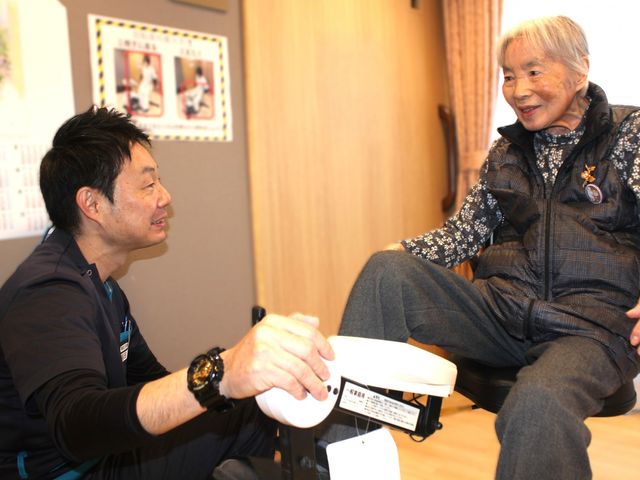 対話するスタッフと入居者 機能訓練室 親しみやすいスタッフが、入居者と共に安心できる支援を提供しています。
