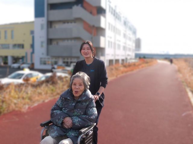 介助の様子　外観 外観 車椅子の方とスタッフがリラックスした雰囲気で外を一緒に散策しています。リラックスできる環境が魅力です。
