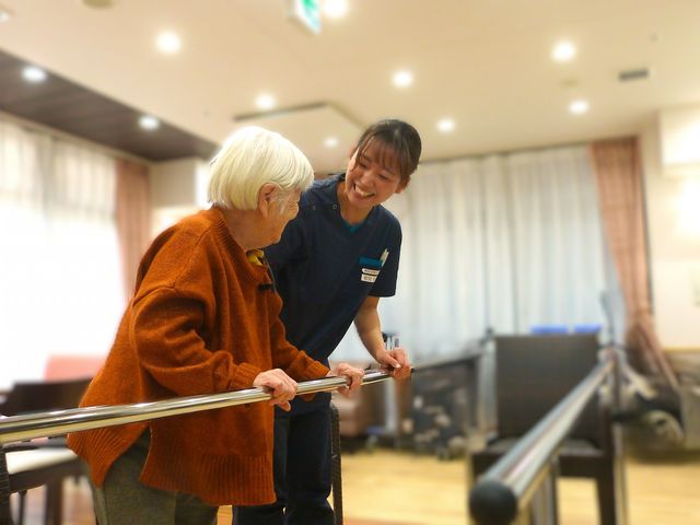 高齢者とスタッフの交流 機能訓練室 スタッフと高齢者が和やかに交流しながら、サポートを受けている様子です。