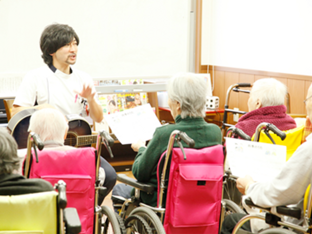 活動中の利用者とスタッフ 多目的室 音楽活動が行われている多目的室です。利用者の方々が楽しそうに参加されています。