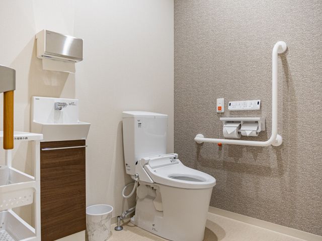 手すり付きトイレ トイレ   手すりが複数設置された、使いやすそうなトイレです。壁際のスペースも広めで、介助しやすい環境に見えます。